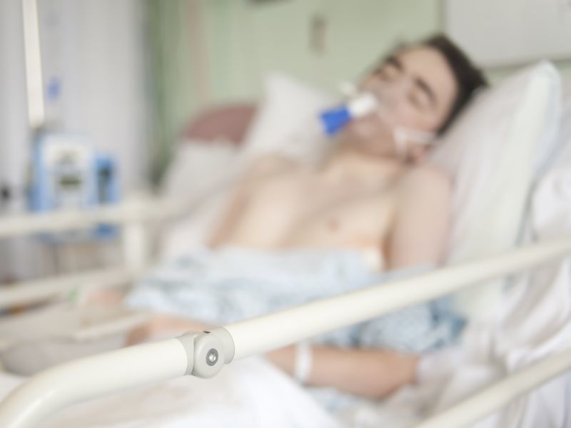 young man in hospital bed with breathing mask