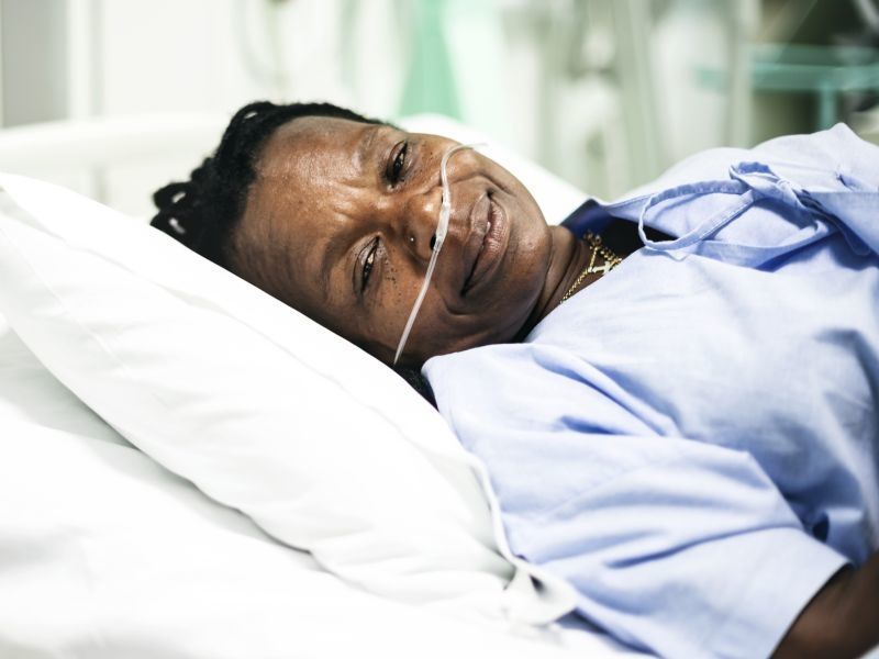 older woman lying in hospital bed with intranasal tubes for breathing