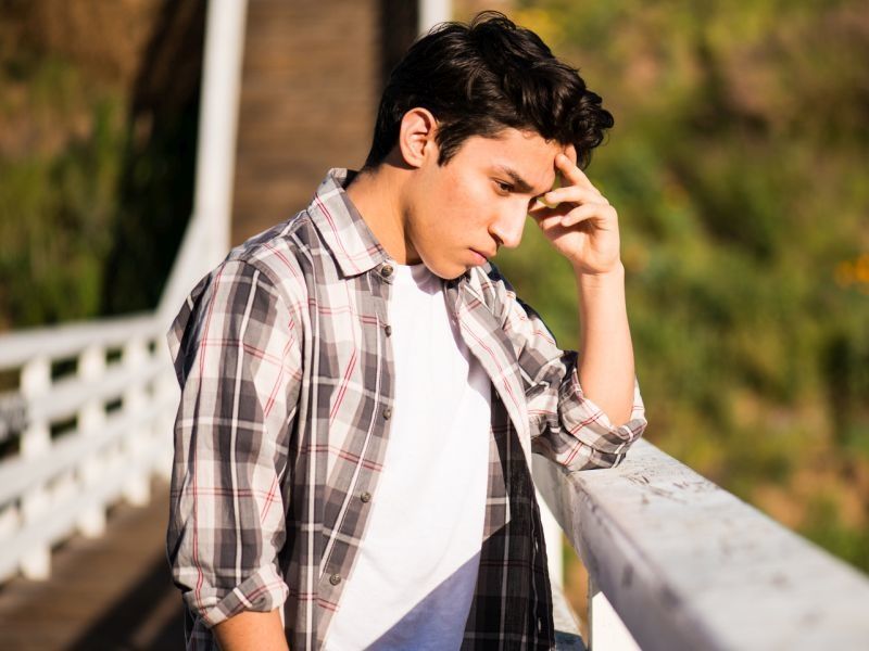 teen boy standing on bridge looking stressed