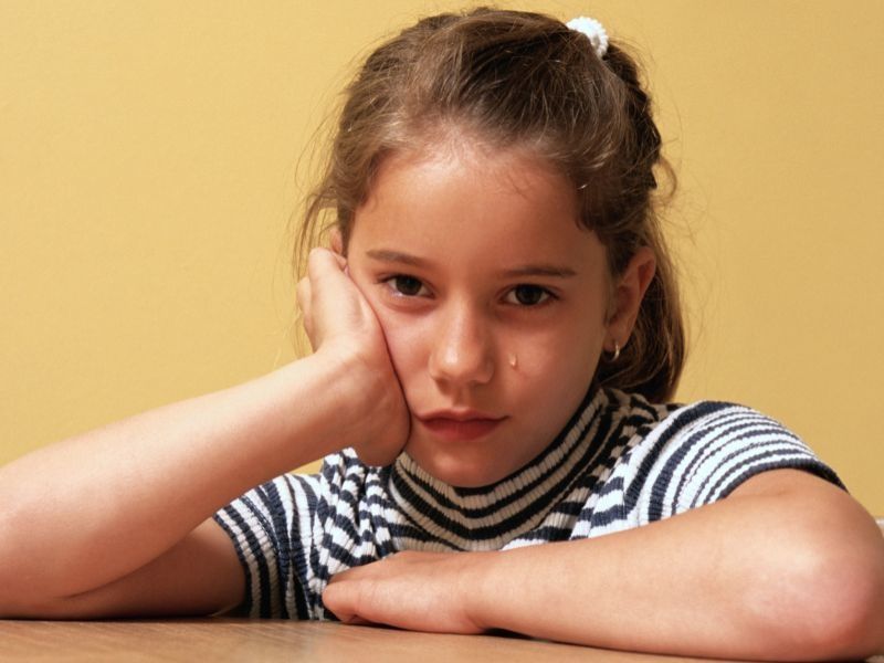 young girl sitting at table crying