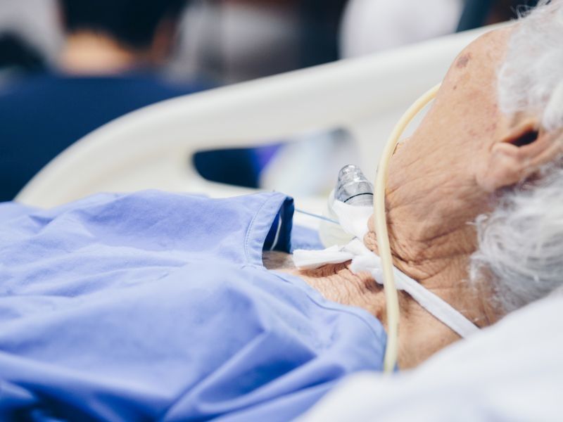 older woman in hospital bed with breathing tube