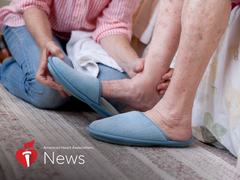 woman sitting on floor helping older woman sitting on bed put on blue slippers 